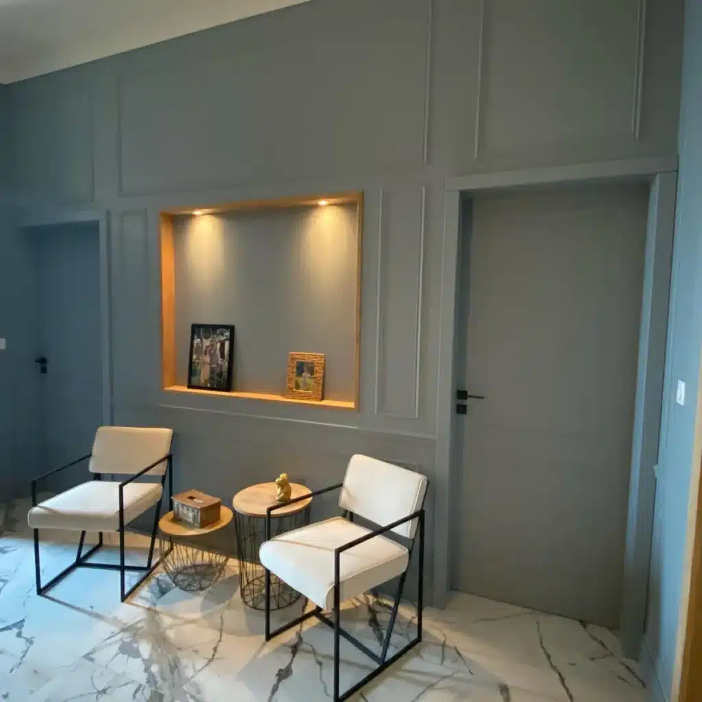 accent-wall-seating Mur accentué avec des moulures intégrées, une niche éclairée et des chaises modernes, mettant en valeur des menuiseries intérieures élégantes.