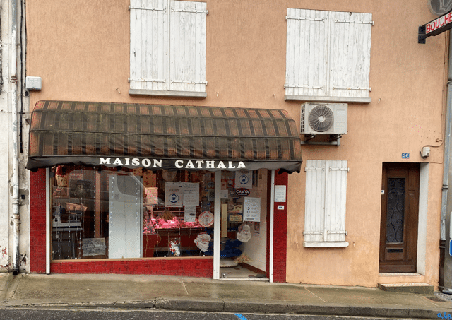 Façade de la boucherie Maison Cathala avec son auvent, volets blancs et décorations de Noël en vitrine.