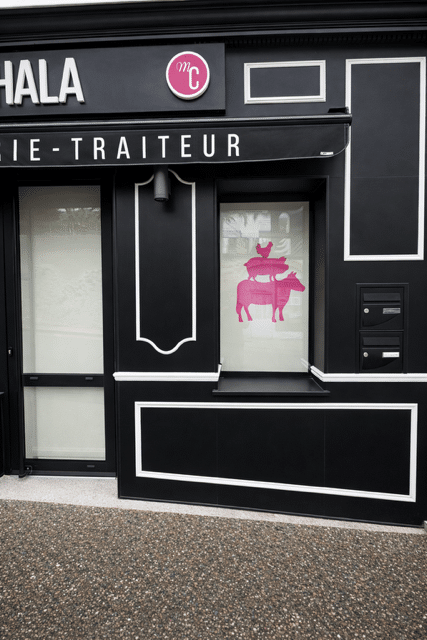 Façade noire de la boucherie traiteur HALA avec logo rose MC et silhouette d'animaux sur la vitrine.